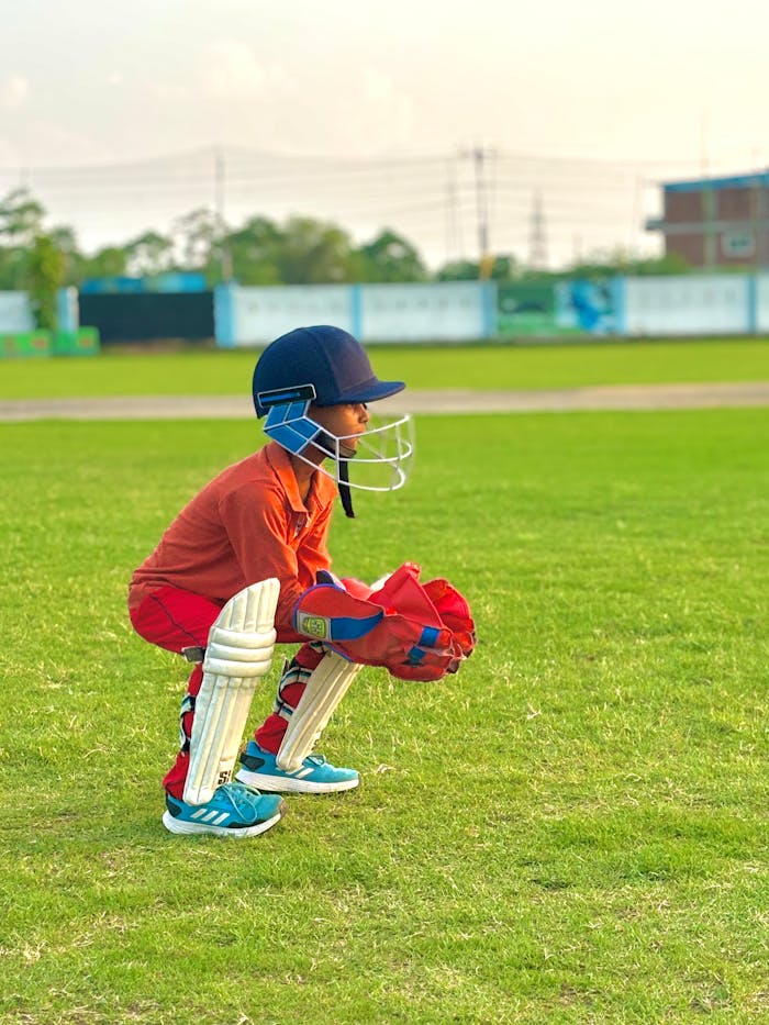 Crafting Captivating Headlines: Your awesome post title goes here A young cricketer crouched on a green field, wearing protective gear and ready to play.