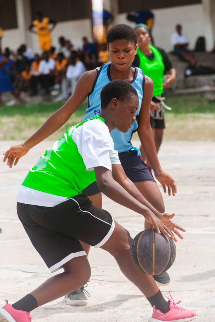 Teenagers in an exciting outdoor basketball game during the day.