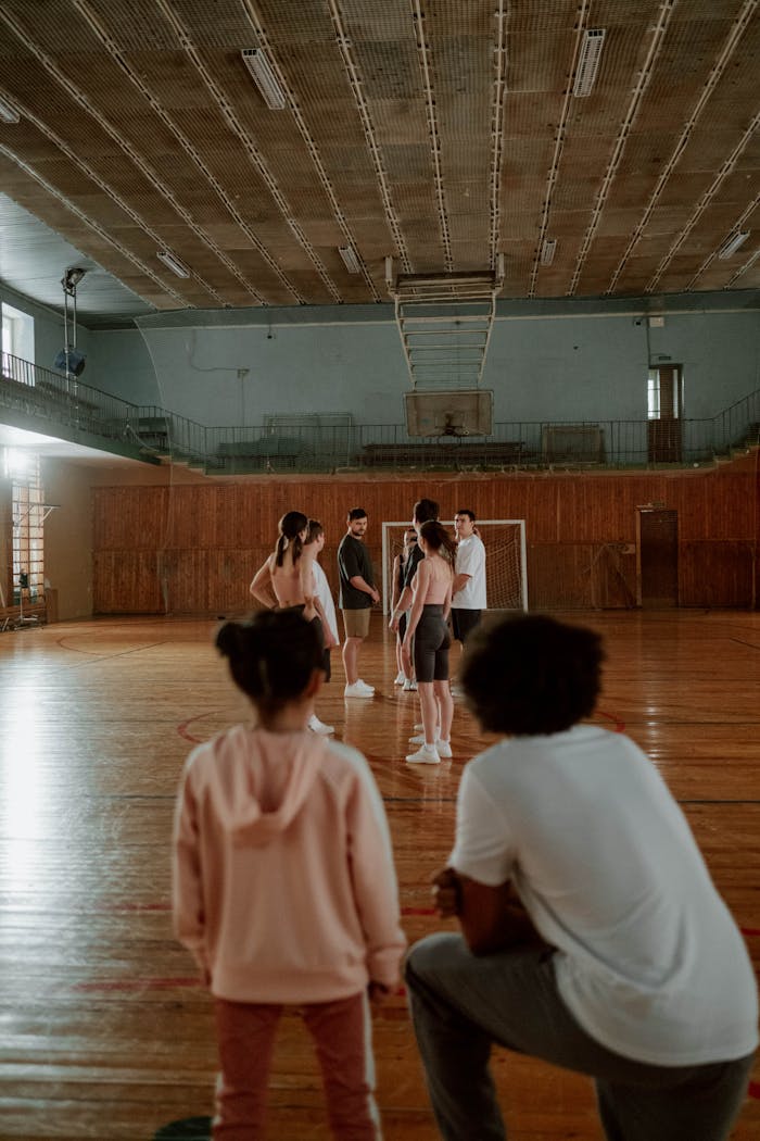 Group of individuals practicing gymnastics indoors with a focus on teamwork and skills.